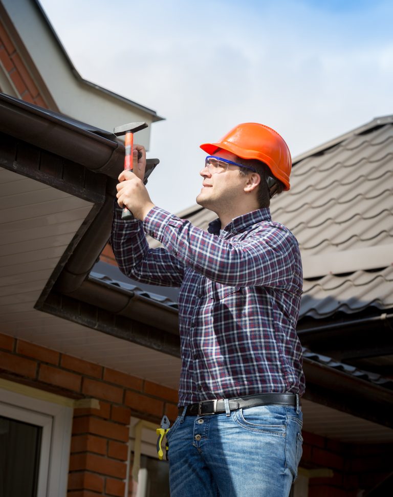 Technician repairing damaged gutters on Burlington home